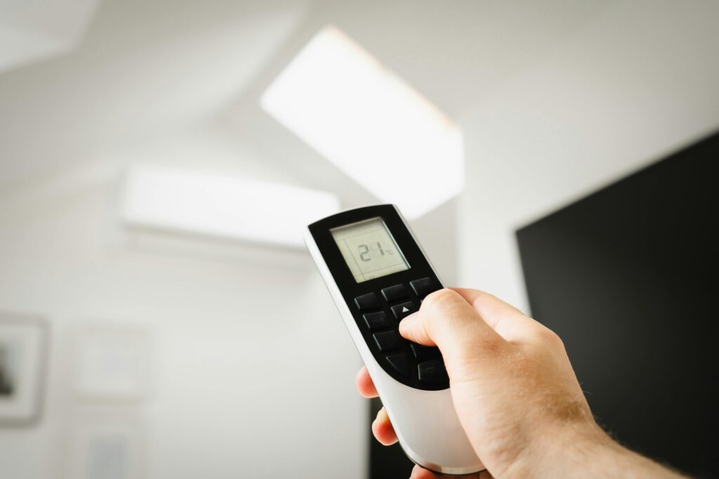 Close-up of a man using a remote to control air conditioning indoors.